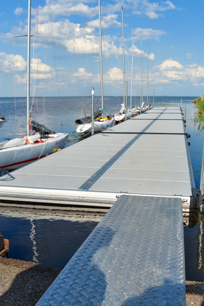 Landgång vid en lång EasyFloat-flytbrygga med mindre segelbåtar förtöjda längs sidorna