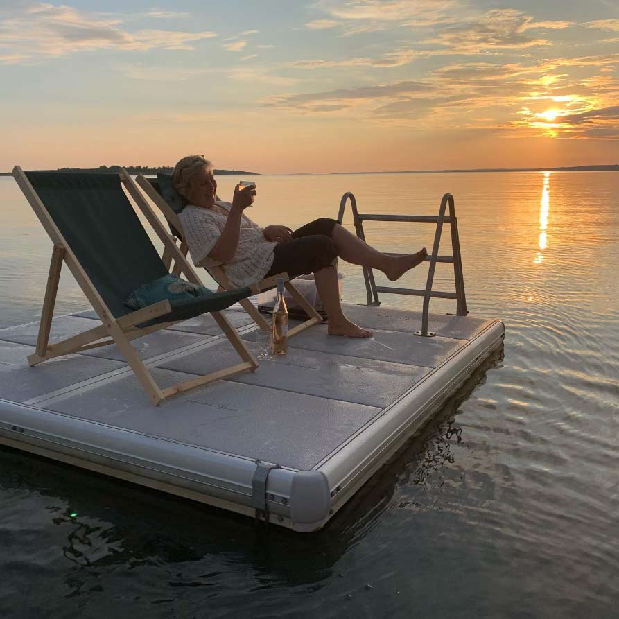 EasyFloat-Plattform mit Badeleiter und Sonnenliegen auf einem See bei Sonnenuntergang
